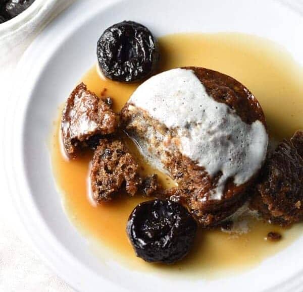 a plate of Sticky Toffee Pudding with sauce and prunes