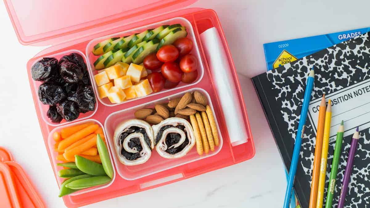 a lunchbox packed with Ham and California Prune Pinwheels, prunes and other finger foods