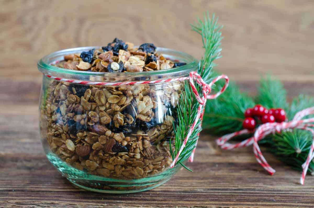a bowl of Christmas granola with striped ribbon and greenery