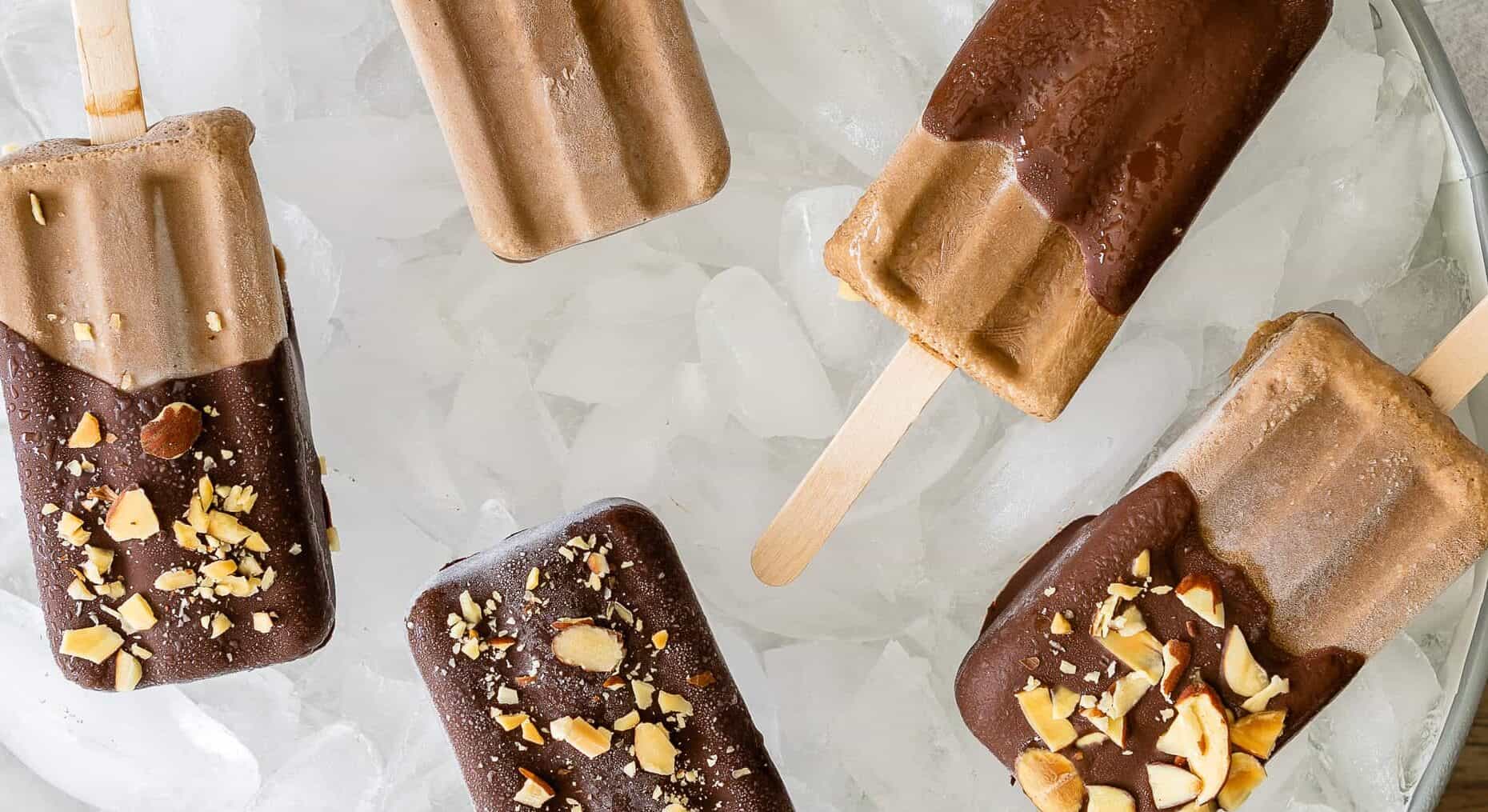 Creamy Prune Caramel Mocha Pops covered in chocolate and coated in nuts on a tray of ice