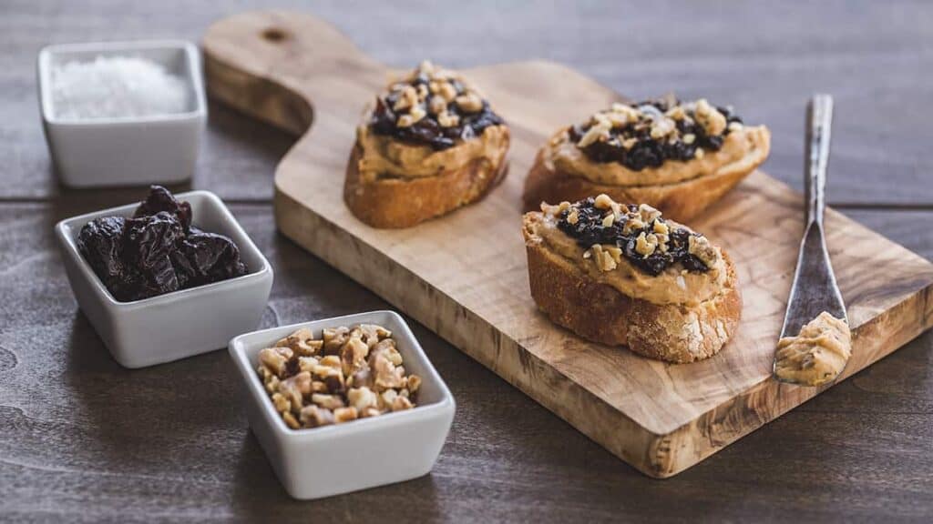 pieces of crostini topped with white beans, prunes and walnuts