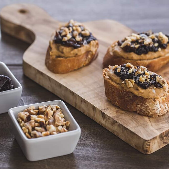 pieces of crostini topped with white beans, prunes and walnuts