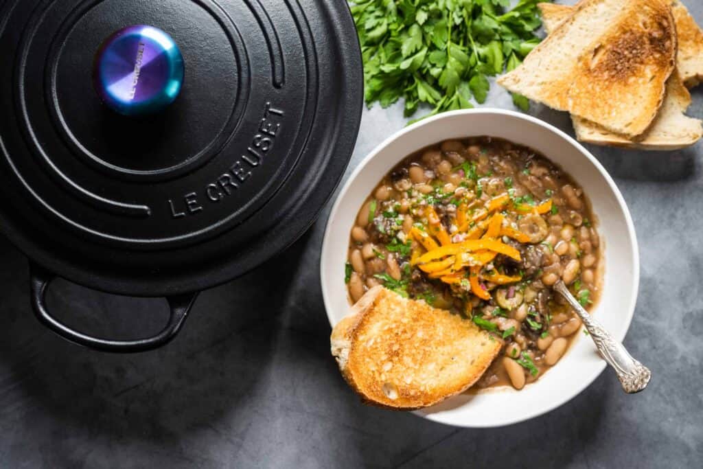 A black cast iron pot next to a bowl of Beans Marbella