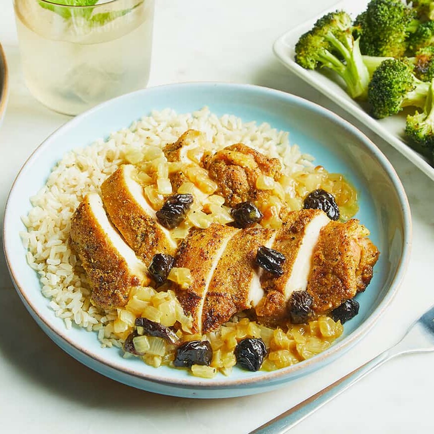 a plate filled with rice and topped with Chicken Curry with California Prunes and a side of broccoli