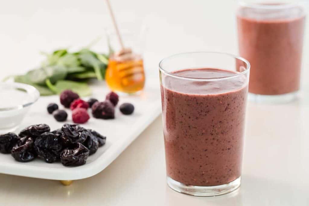 two glasses of Purple Power Smoothies and a plate with berries and prunes