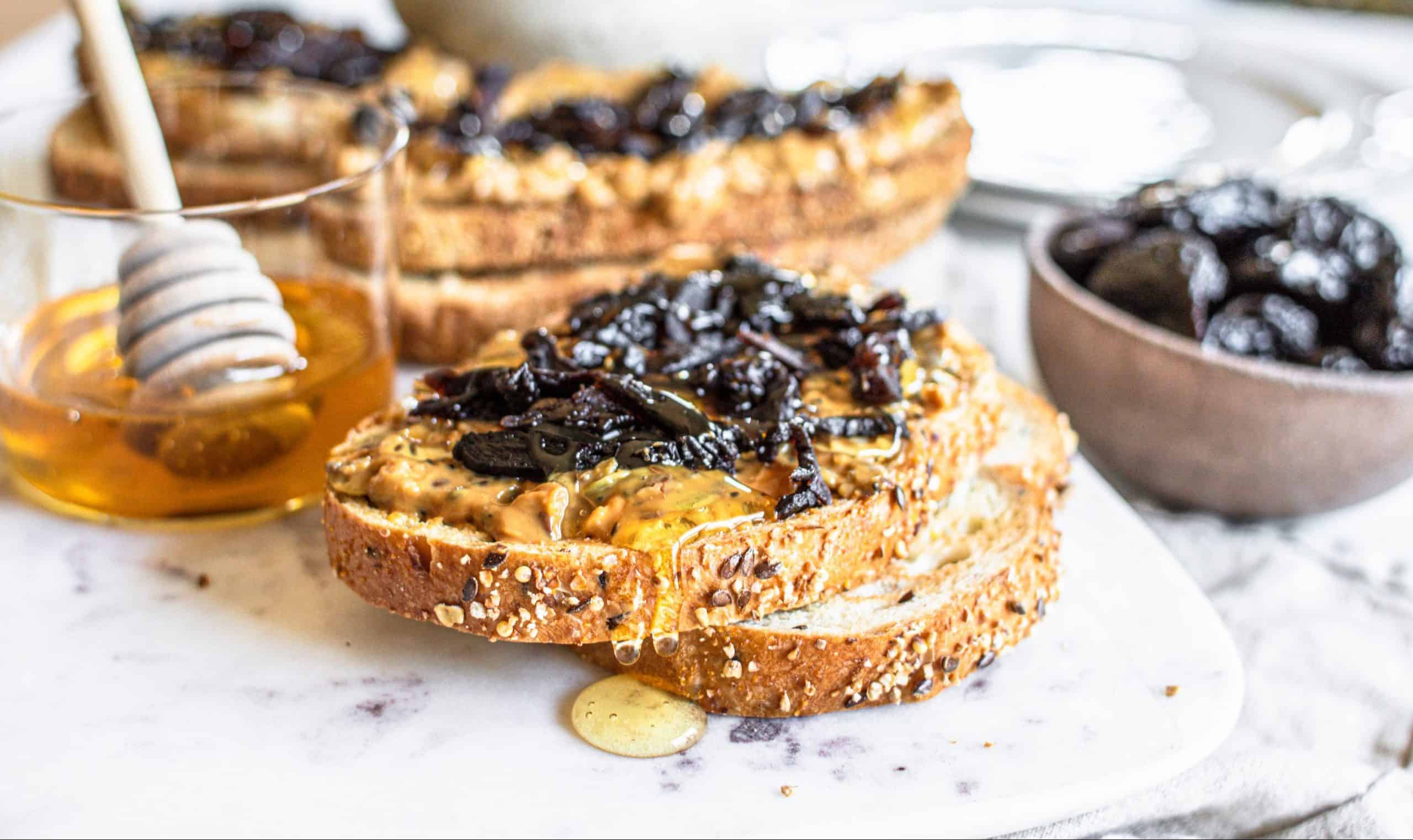 slices of bread topped with peanut butter, honey and prunes