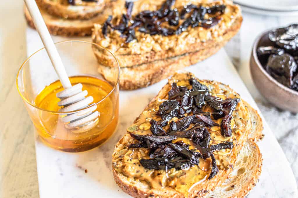a slice of bread topped with Prunes, Nut Butter and Honey