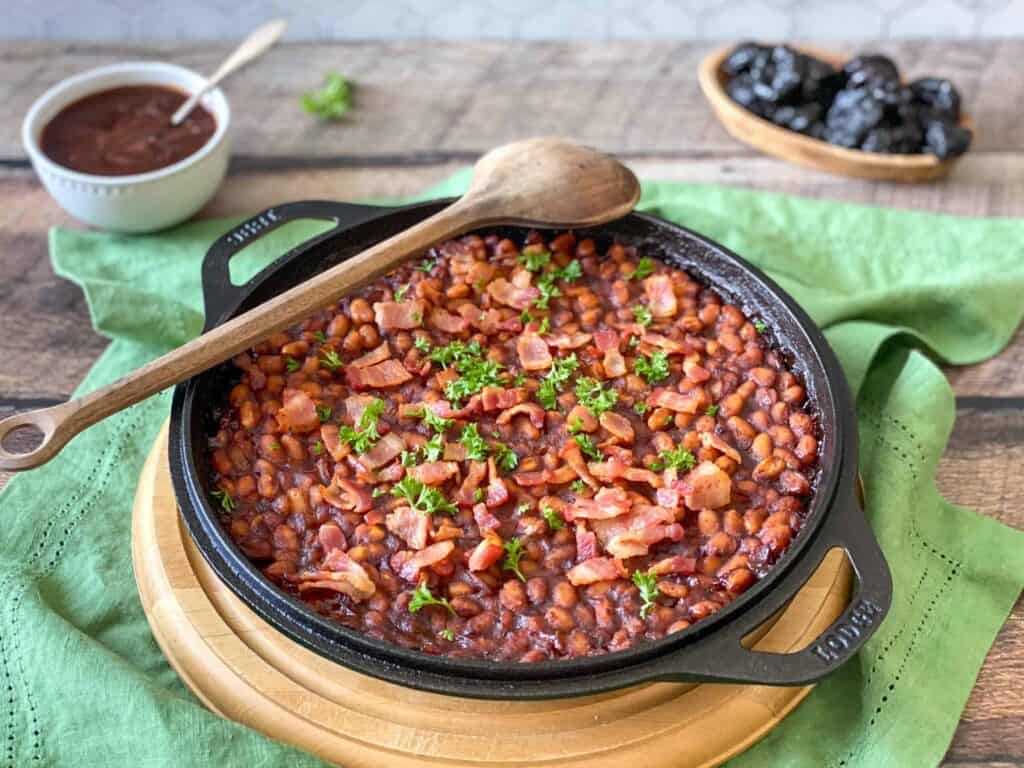a cast iron skillet full of Naturally Sweetened Baked Beans Recipe with California Prune BBQ Sauce