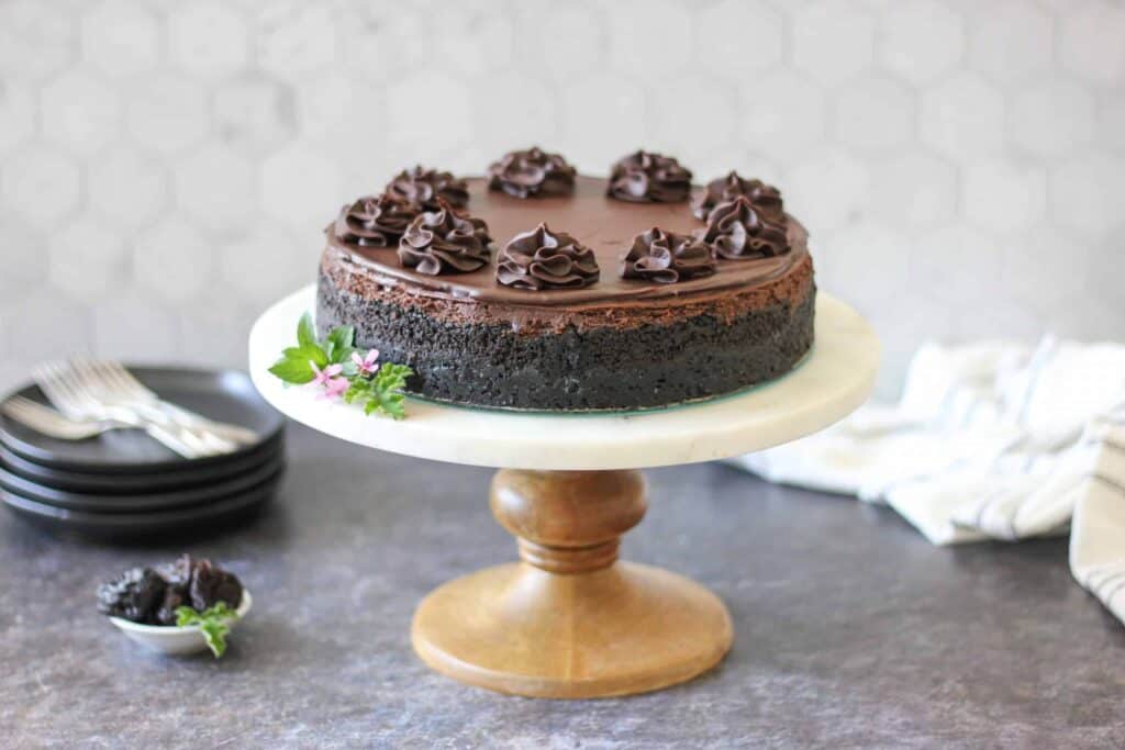 a cake plate topped with Double Chocolate Cheesecake and a stack of black plates