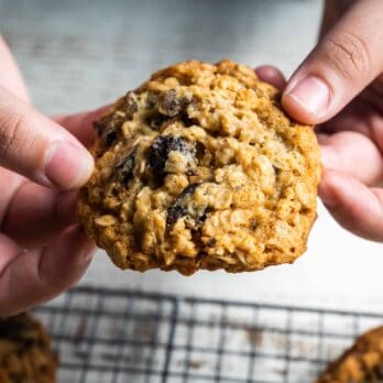 two hands snapping an old-fashioned chewy oatmeal cookie with chocolate