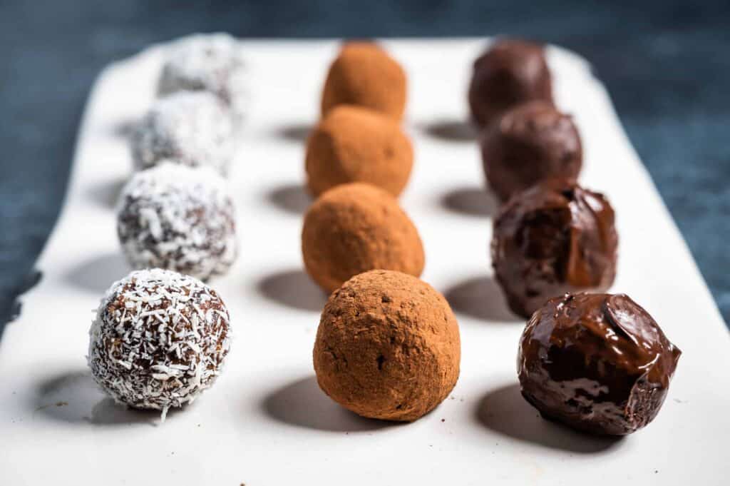 a tray with dark chocolate bliss balls coated in three different types of toppings