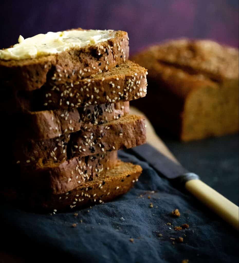 a stack of sliced of Banana Bread on a napkin with a knife