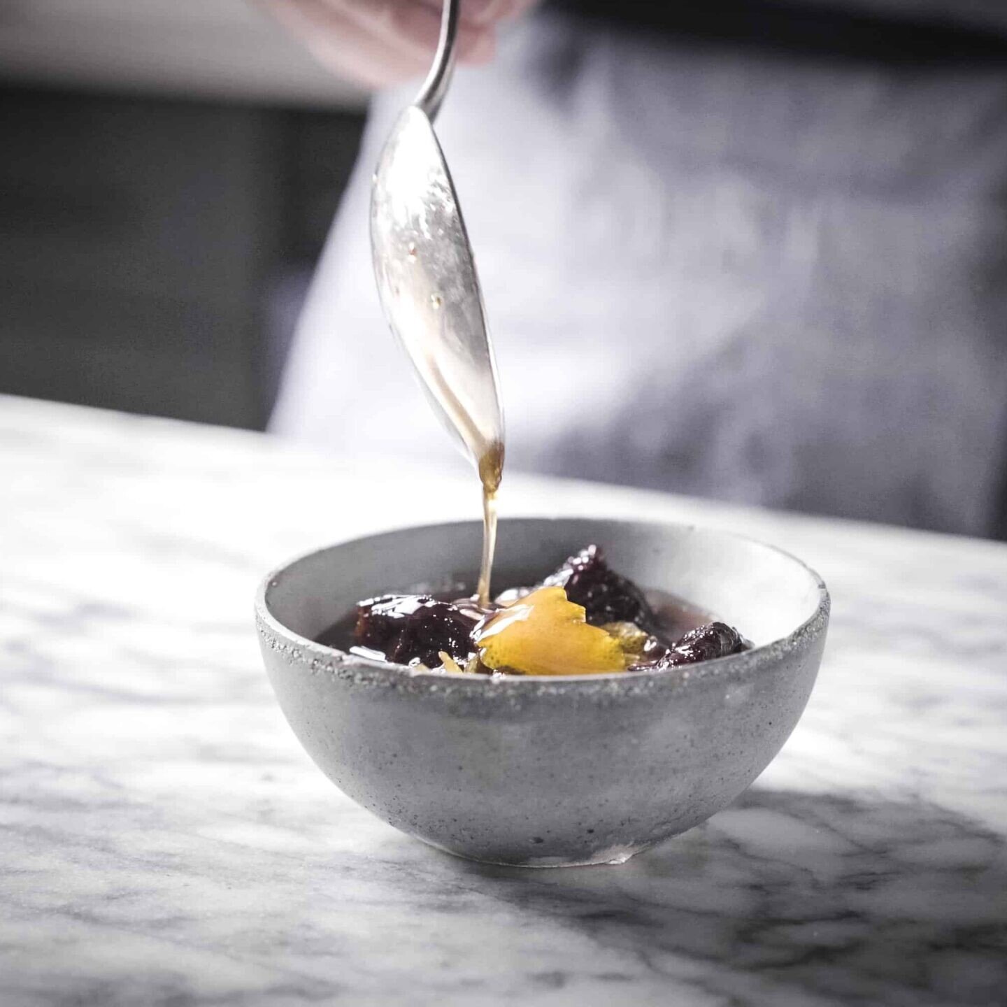 a spoon drizzling California Prune Syrup with Pink Peppercorn into a bowl