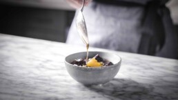 a spoon drizzling California Prune Syrup with Pink Peppercorn into a bowl