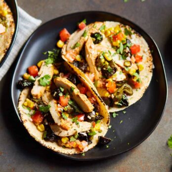 a black plate with two Chicken Tacos with California Prunes Salsa