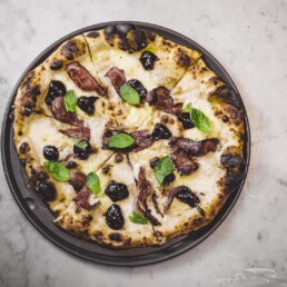a tray of Bacon Jam pizza with prunes