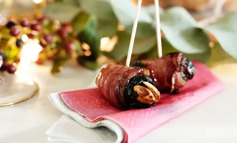 a cocktail napkin with two of Jamie Oliver's Devils on Horseback