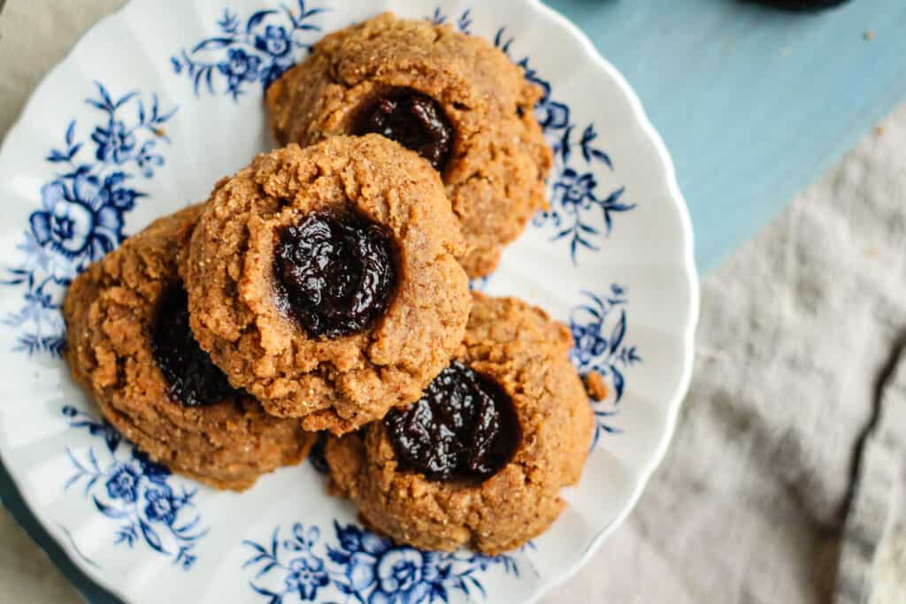 Grain + gluten free Prune and Almond Butter thumbprint cookies from Meg of This Mess is Ours. Four cookies on a blue and white plate