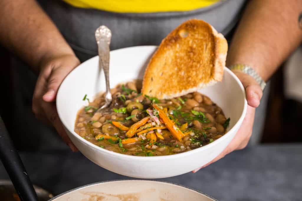 Person holding a bowl full of Beans Marbella