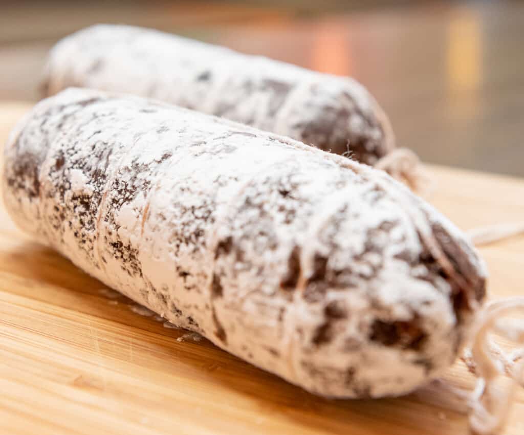 two rolls of chocolate salami on a wooden cutting board