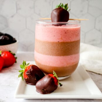 chocolate layered smoothie in a glasses on a plate with chocolate covered strawberries