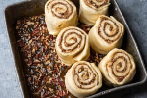 Buns are placed in a pan on top of the sticky topping