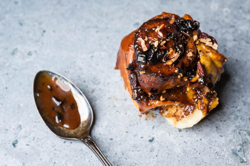 one pecan sticky bun and a spoon coated in glaze