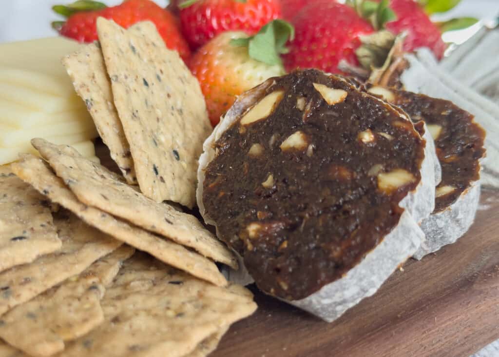 slices of Peppered Vegan Salami by Jerry James Stone on a board with crackers and strawberries