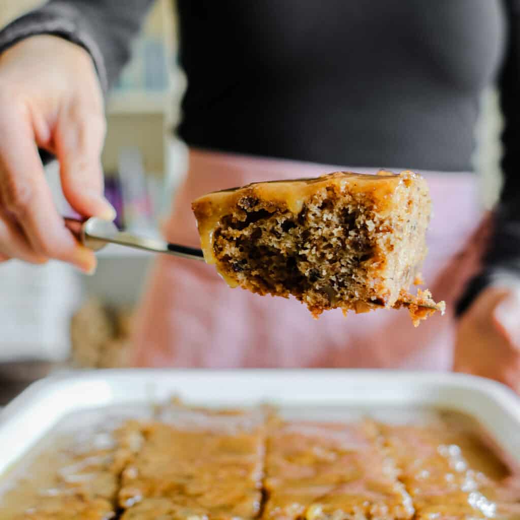 woman pulling out a slice of old-fashioned prune cake