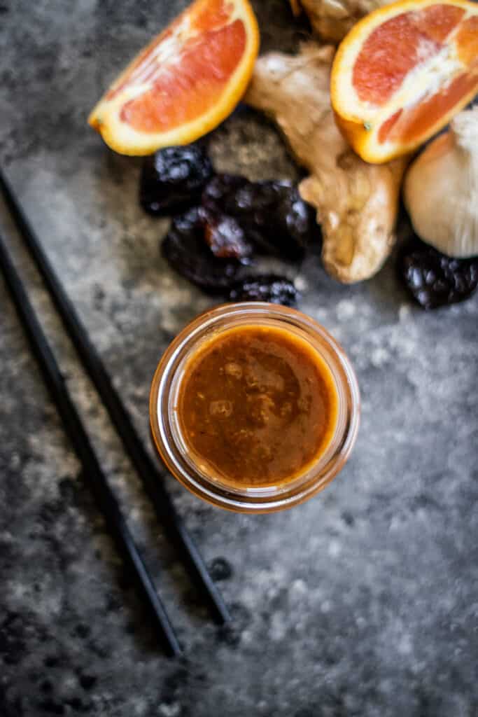 jar of teriyaki sauce with fruit and prunes in the background