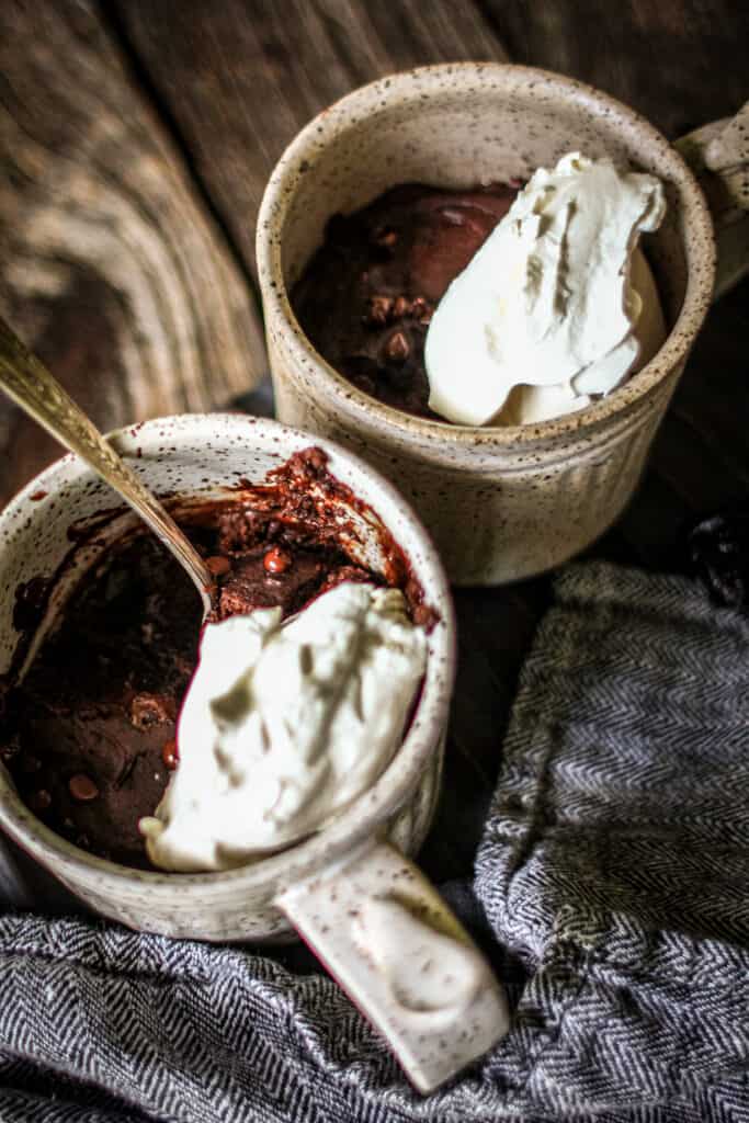 two mugs filled with chocolate cake topped with whipped cream