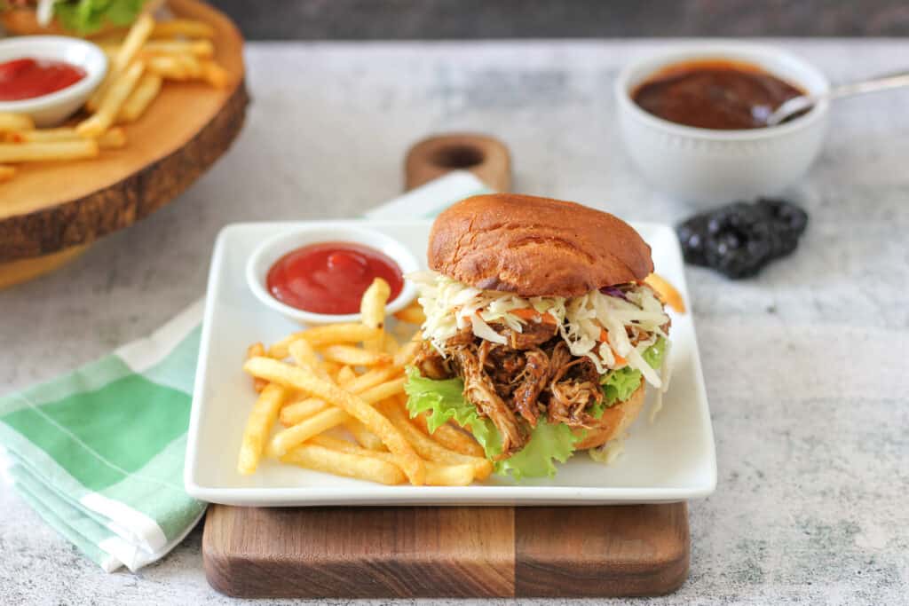 BBQ pulled chicken sandwiches made using slow cooker pulled chicken recipe on a plate with french fries and ketchup