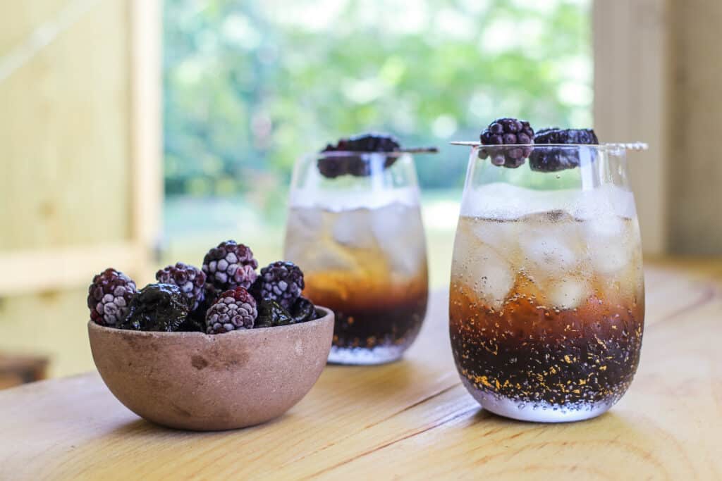 Two glasses of "Stormy Sparkler" cocktails with prune juice cocktail with sparkling wine or sparkling water, black raspberry liqueur and lime