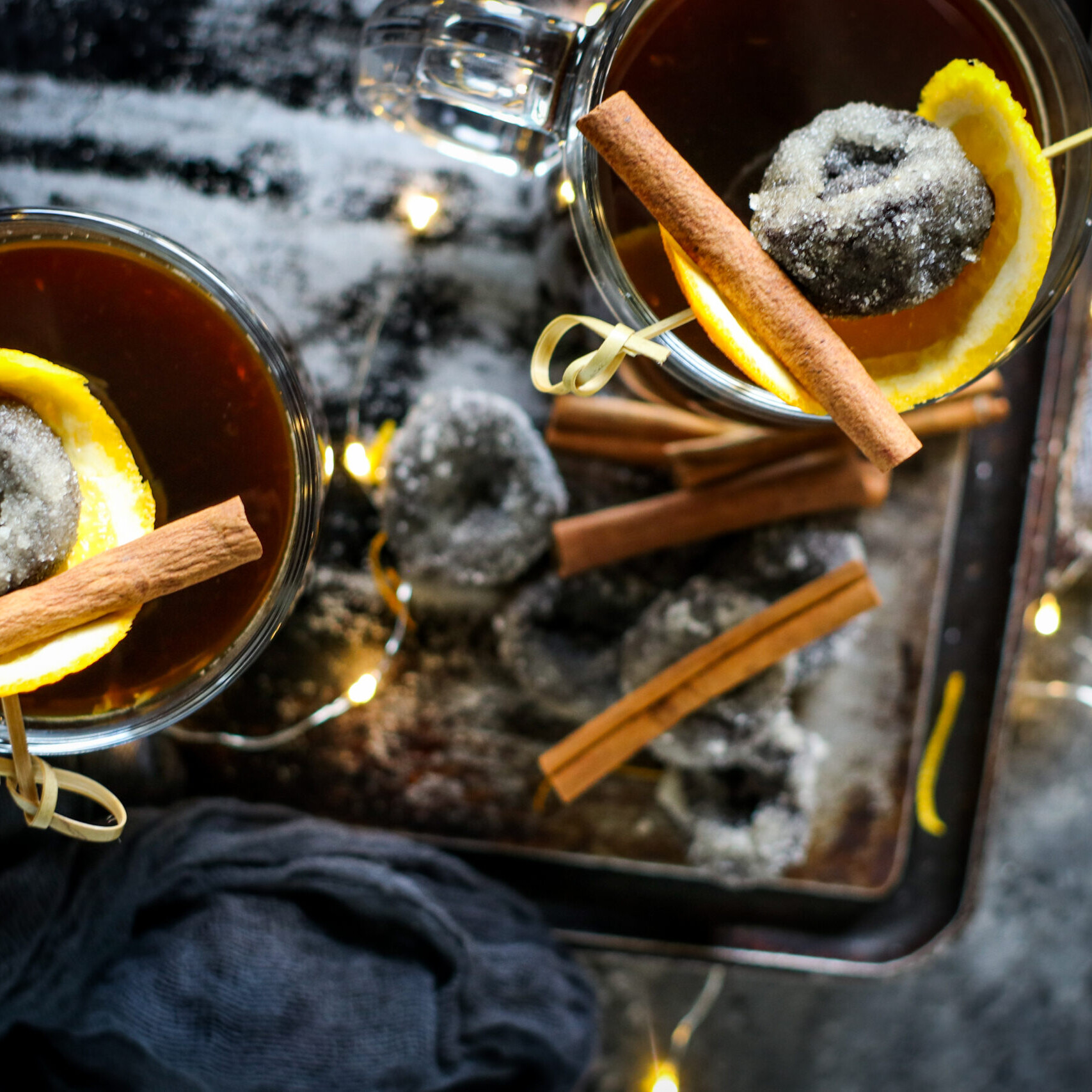 Two glasses of Warm Sugar Plum Cocktail combines the fragrant blend of spices, prune juice, and rum. Garnished with citrus peel and sugared California Prunes