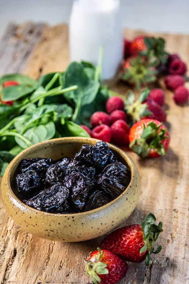Power pairing - a cutting board with prunes, berries, nut milk and spinach
