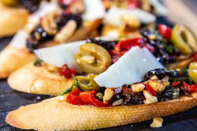 pieces of bruschetta topped with a mediterannean-inspired prune, olive and pepper mixture