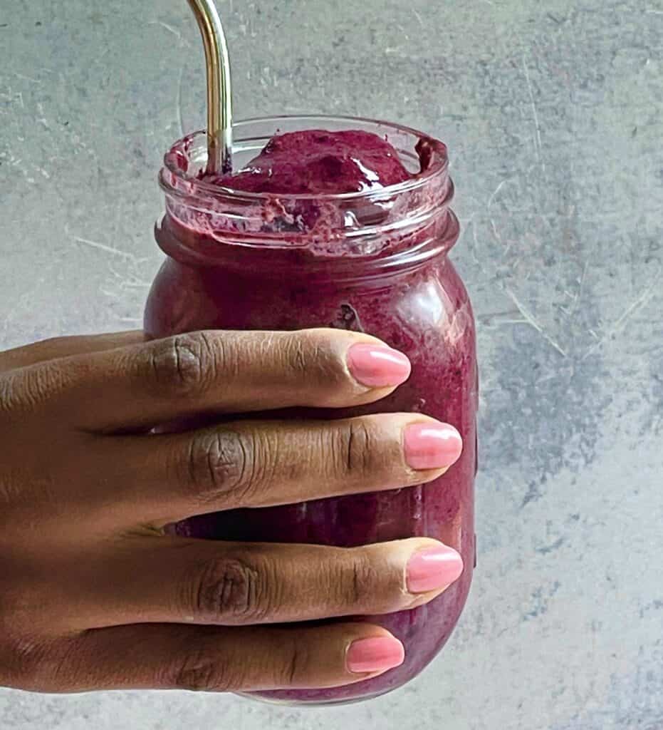 a hand holding a blueberry smoothie