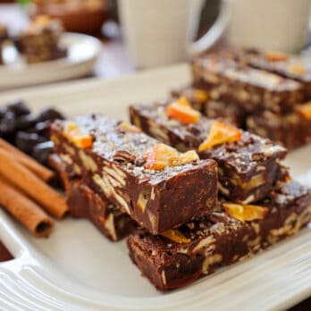 two fudge squares topped with salt and citrus on a tray with prunes and cinnamon