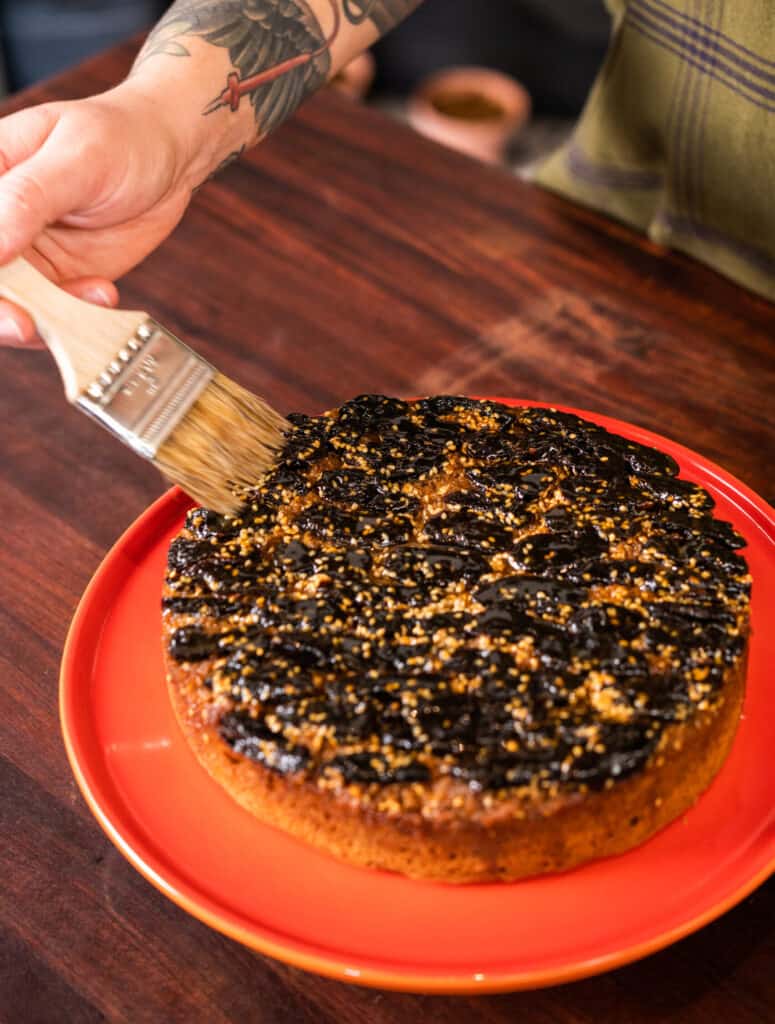 Bronwen Wyatt basting an cake topped with caramelized prunes
