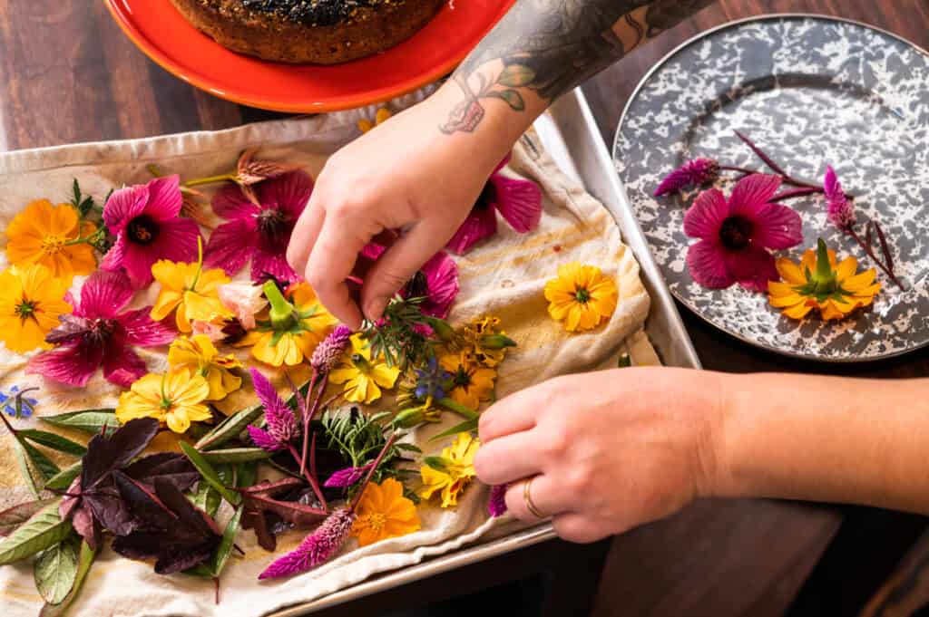 a woman sorting through a tray of edible flowers 
