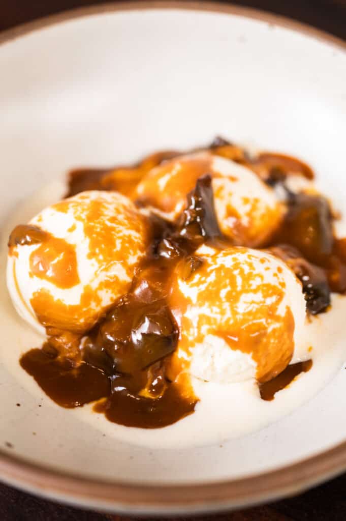 a bowl of ice cream drizzled with spiced prune caramel sauce