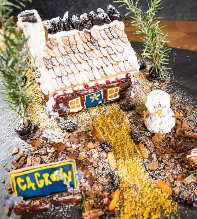 a gingerbread house decorated with dried fruit and nuts