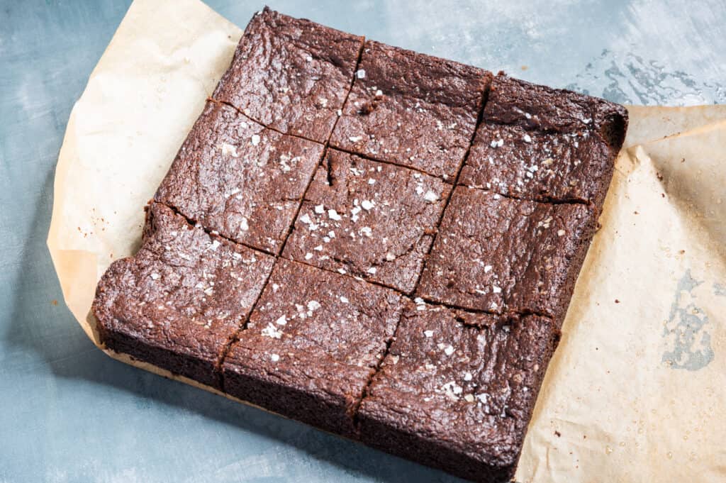 sliced vegan brownies on a sheet of parchment paper