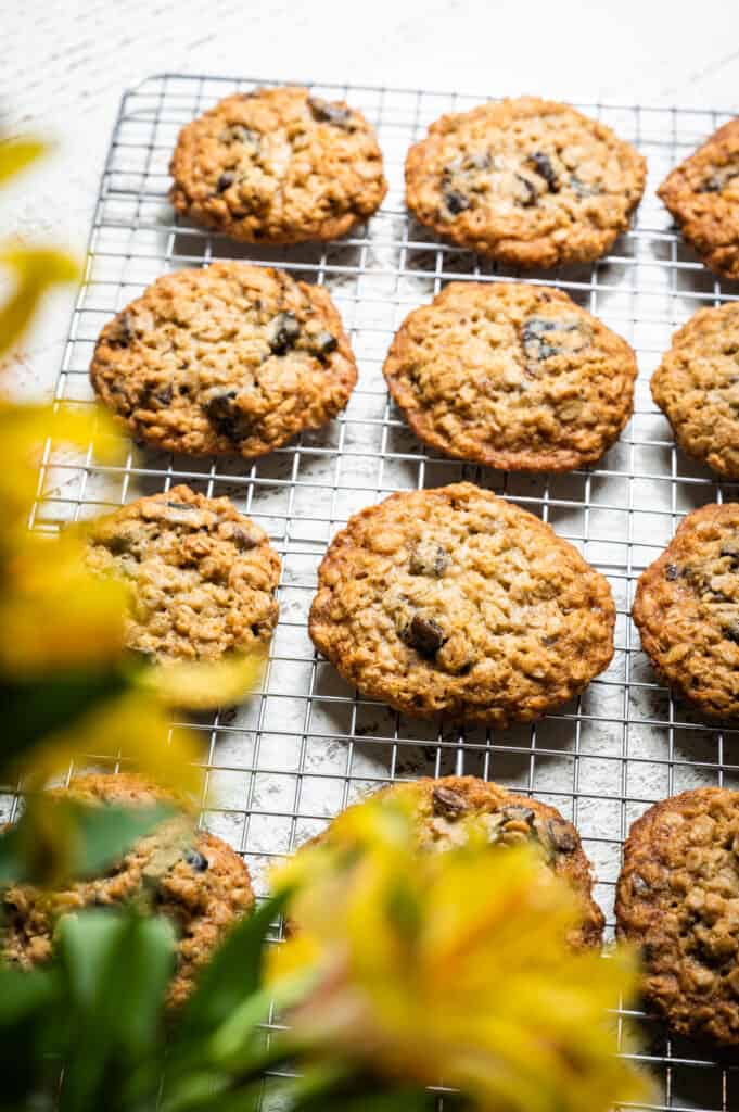 Chewy Oatmeal Chocolate Chip Cookies on a cooling rack with a bouquet of flowers