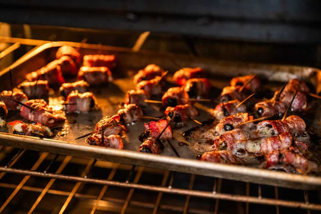 Bacon wrapped prunes baking in the oven Devils on Horseback