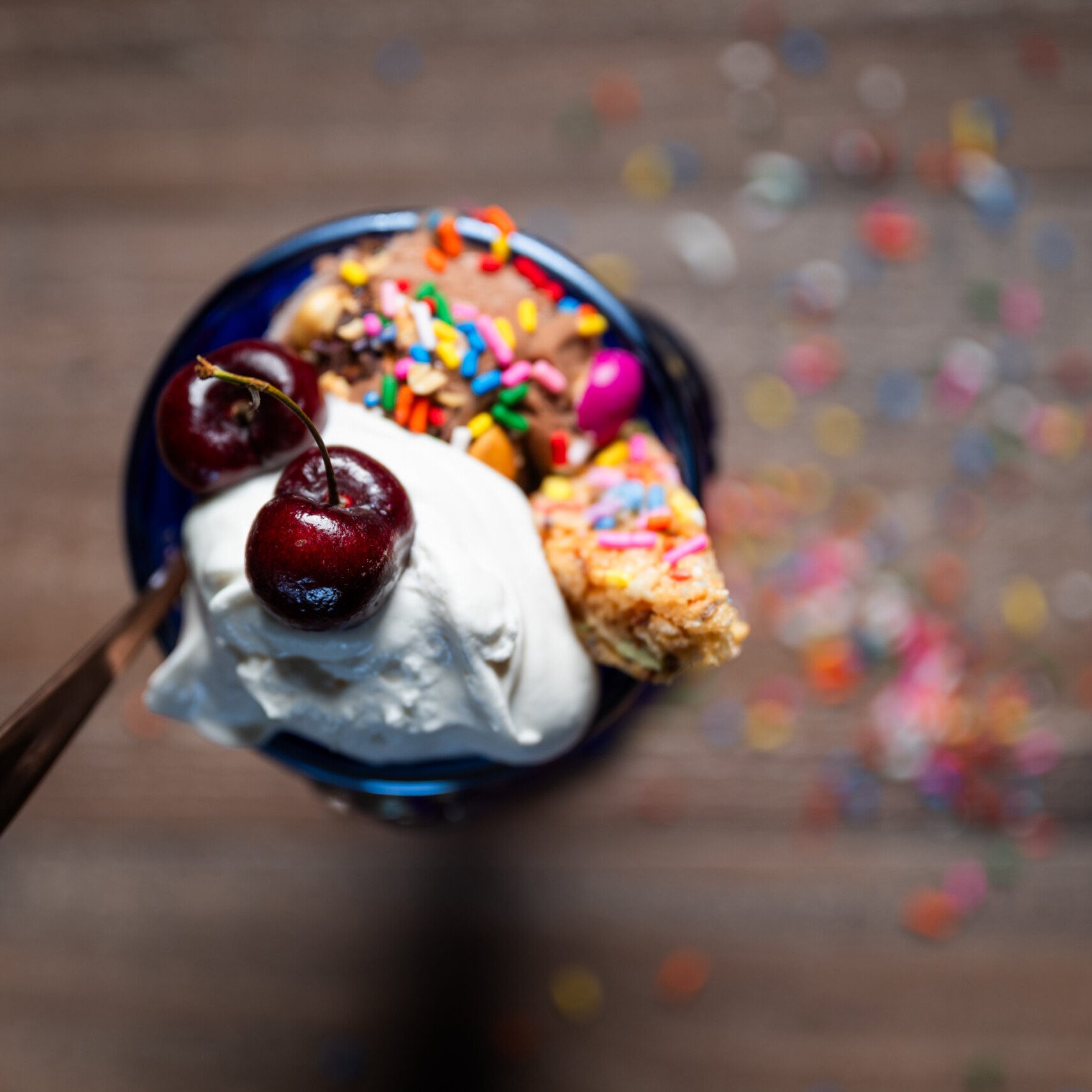 a blue glass filled with Vegan Chocolate Ice Cream (Nice Cream) Sundaes with whipped cream, sprinkles and a cherry