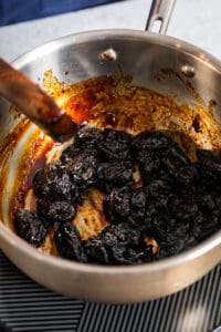 stirring prunes in a pan to make vegan salami
