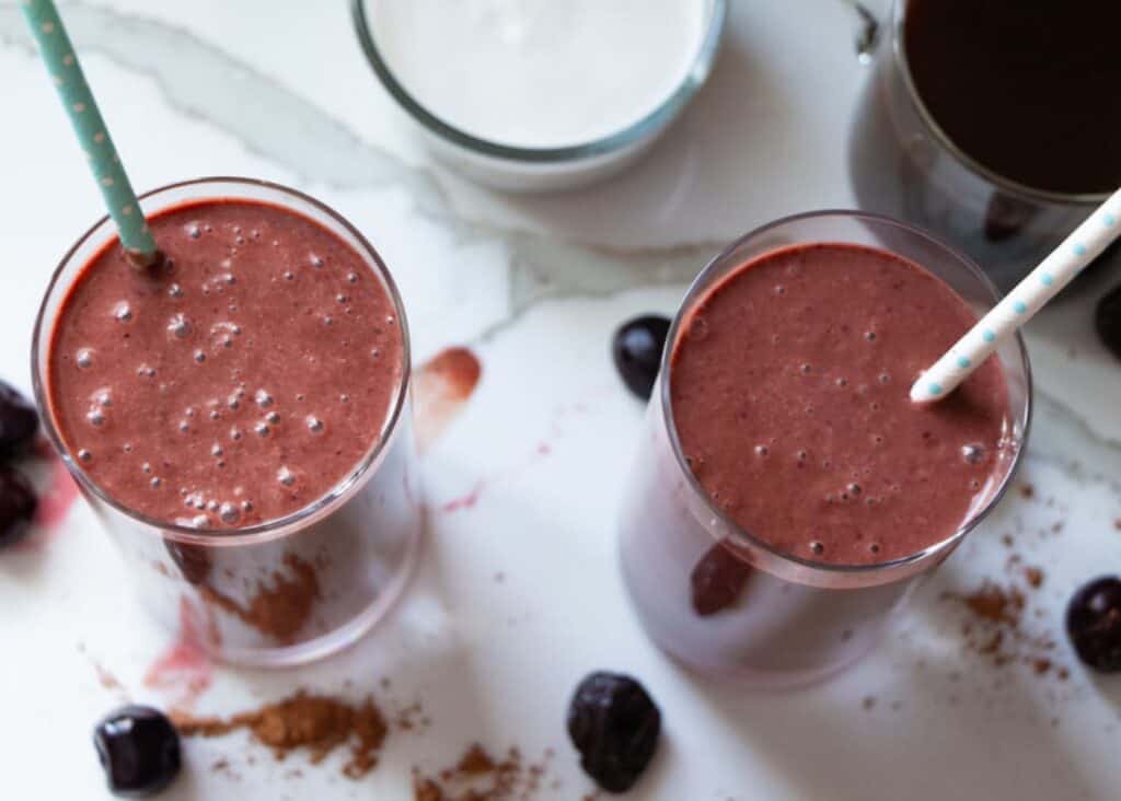 two glasses of vegan chocolate cherry prune smoothie from plant based with amy with a straw