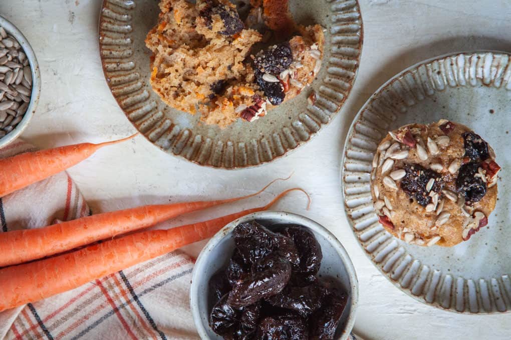 a plate of Carrot Morning Glory Muffins from Eat the Love next to carrots and prunes