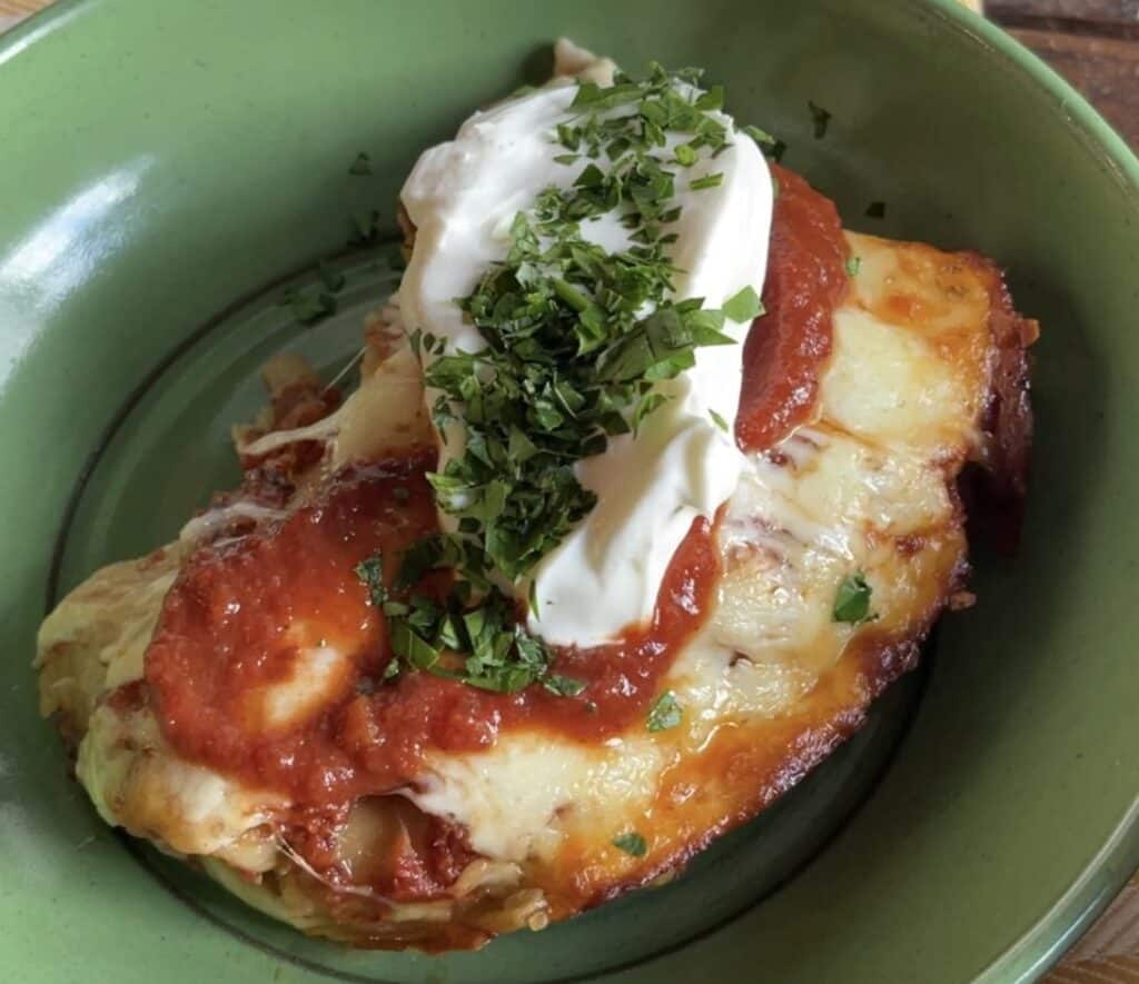 a green bowl with one serving of Teri Turner's Chicken enchiladas with secret sauce